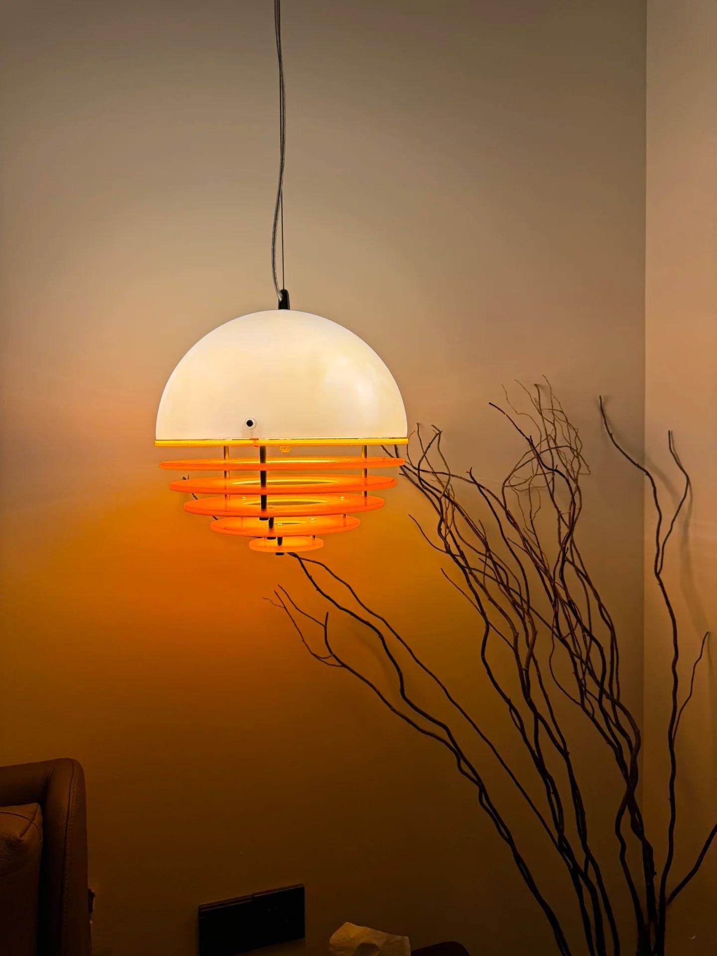 Layered acrylic sunset pendant light casting a warm wall glow