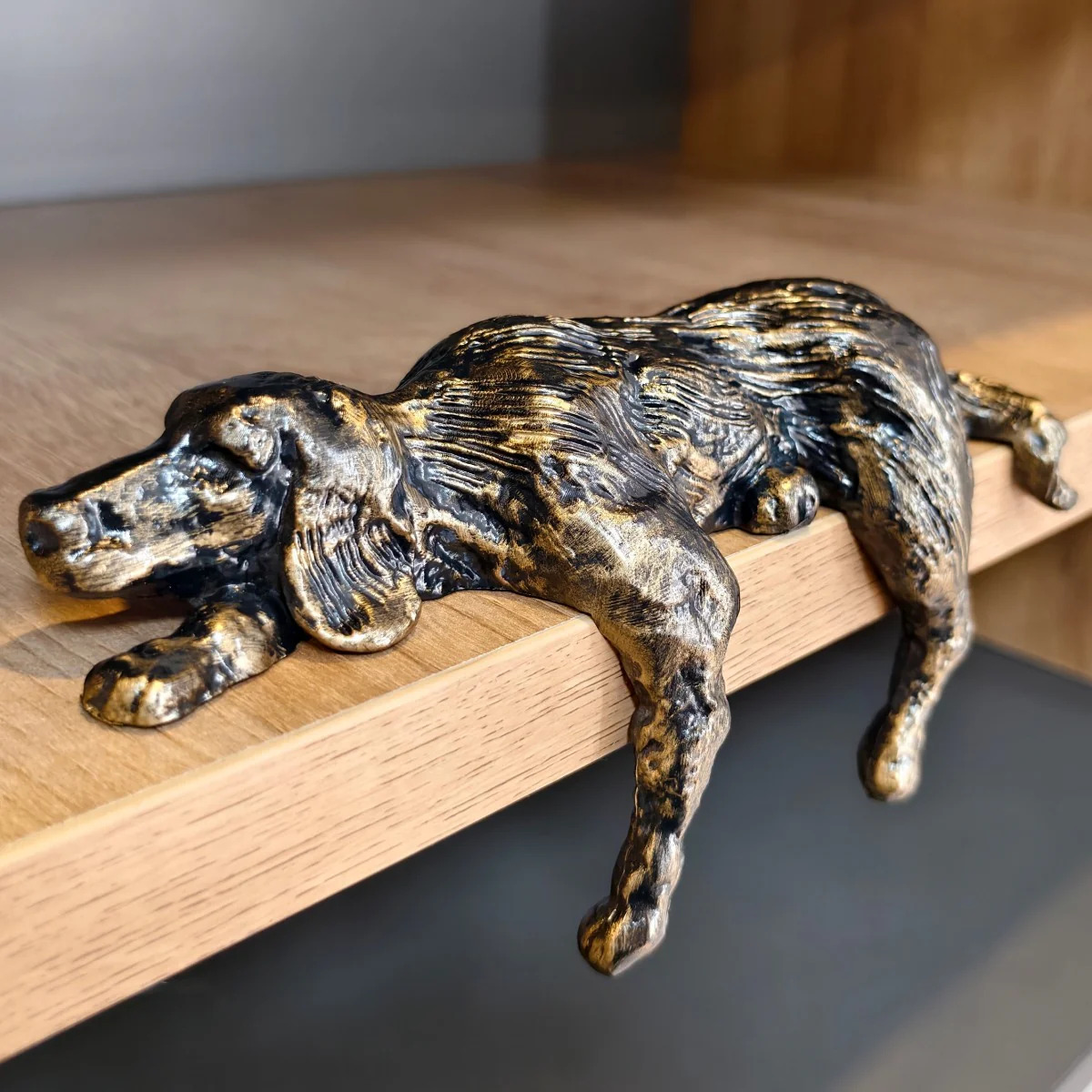 Bronze iron dog sculpture resting along a shelf edge