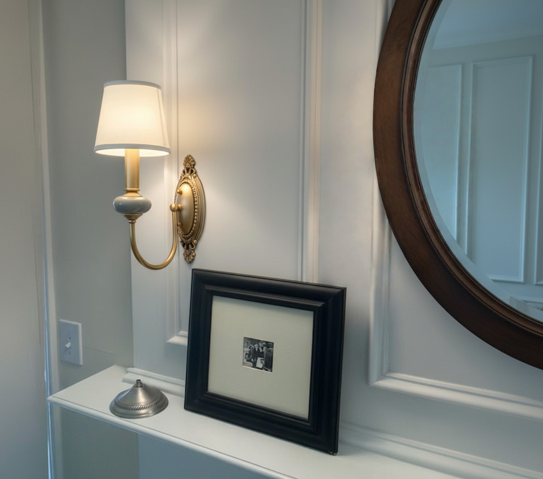Rowanea wall sconce mounted beside a mirror and framed photo