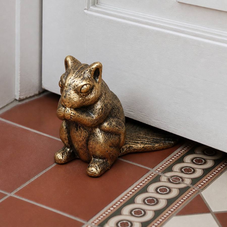 Bronze Guardian door stopper beside a white door on patterned tile