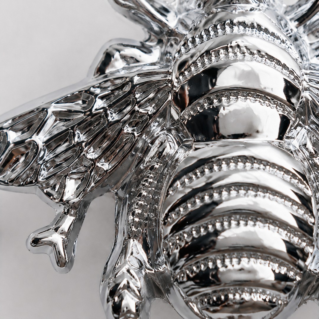 Chrome cabinet handle macro detail showing ribbed bee body