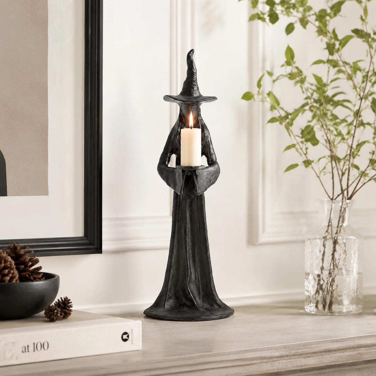Aura single candle black resin candlestick styled on a bright shelf with a lit candle