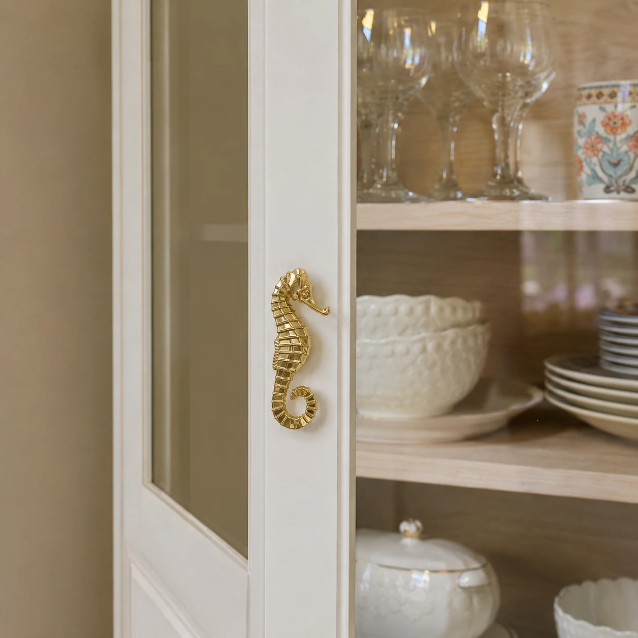 Left Totem Haima brass cabinet handle installed on a light display cabinet