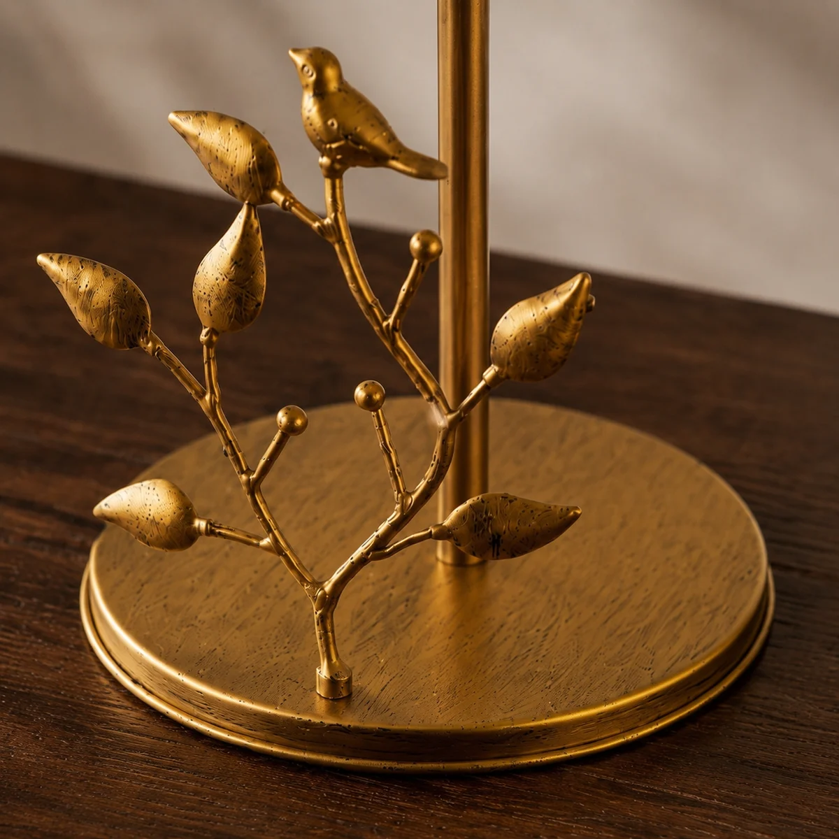 Close detail of the brass base, pole, branch, and bird ornament