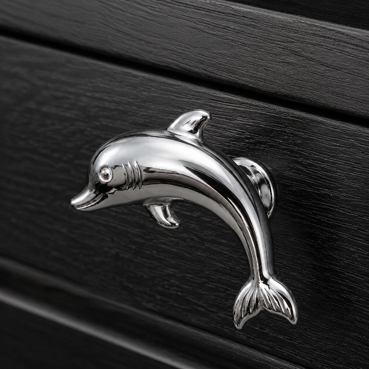 Chrome Dolphin cabinet knob close-up on black cabinet door