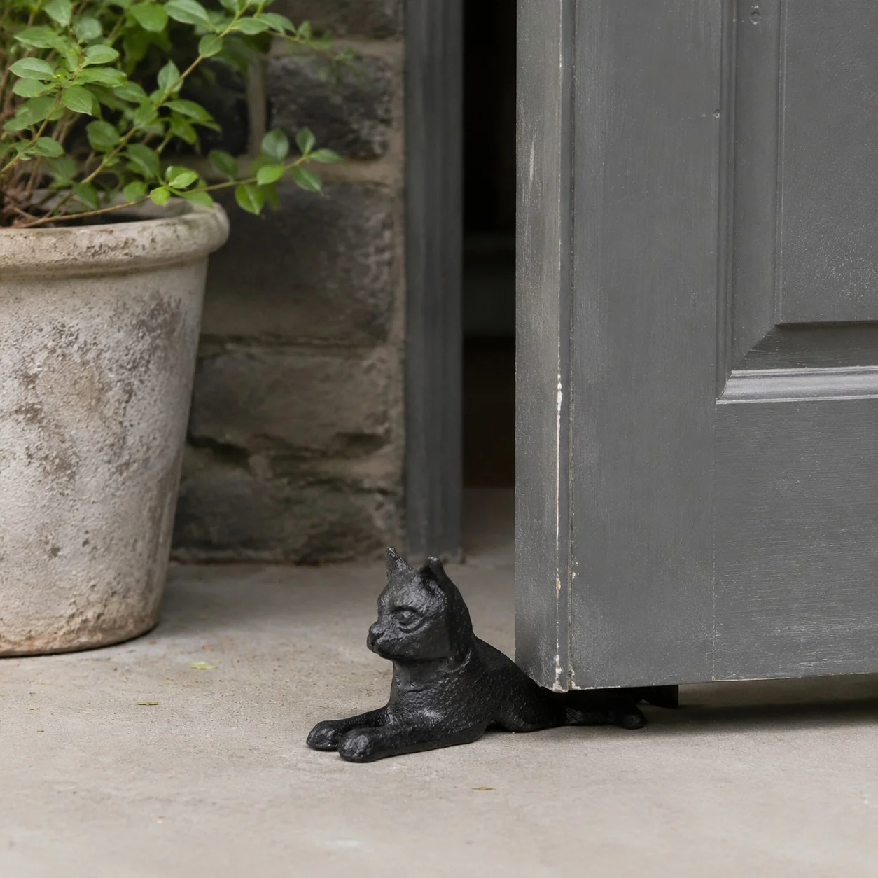 Guardian door stopper holding a gray door near a planter