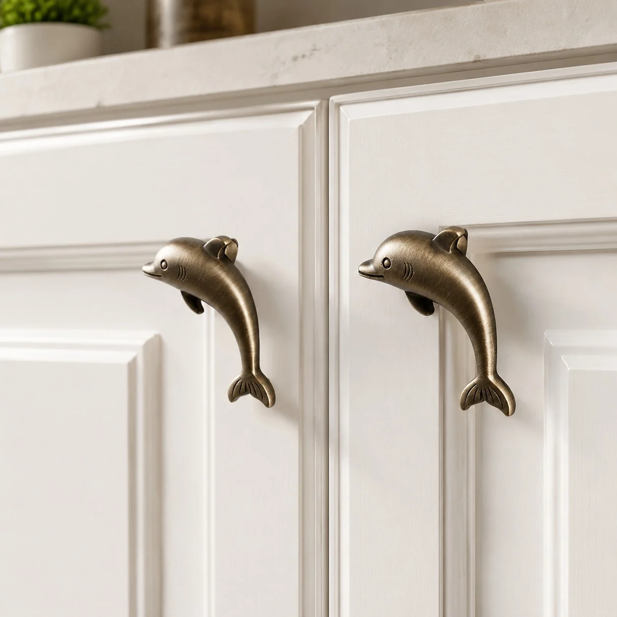 Antique brass dolphin handles on white cabinet doors
