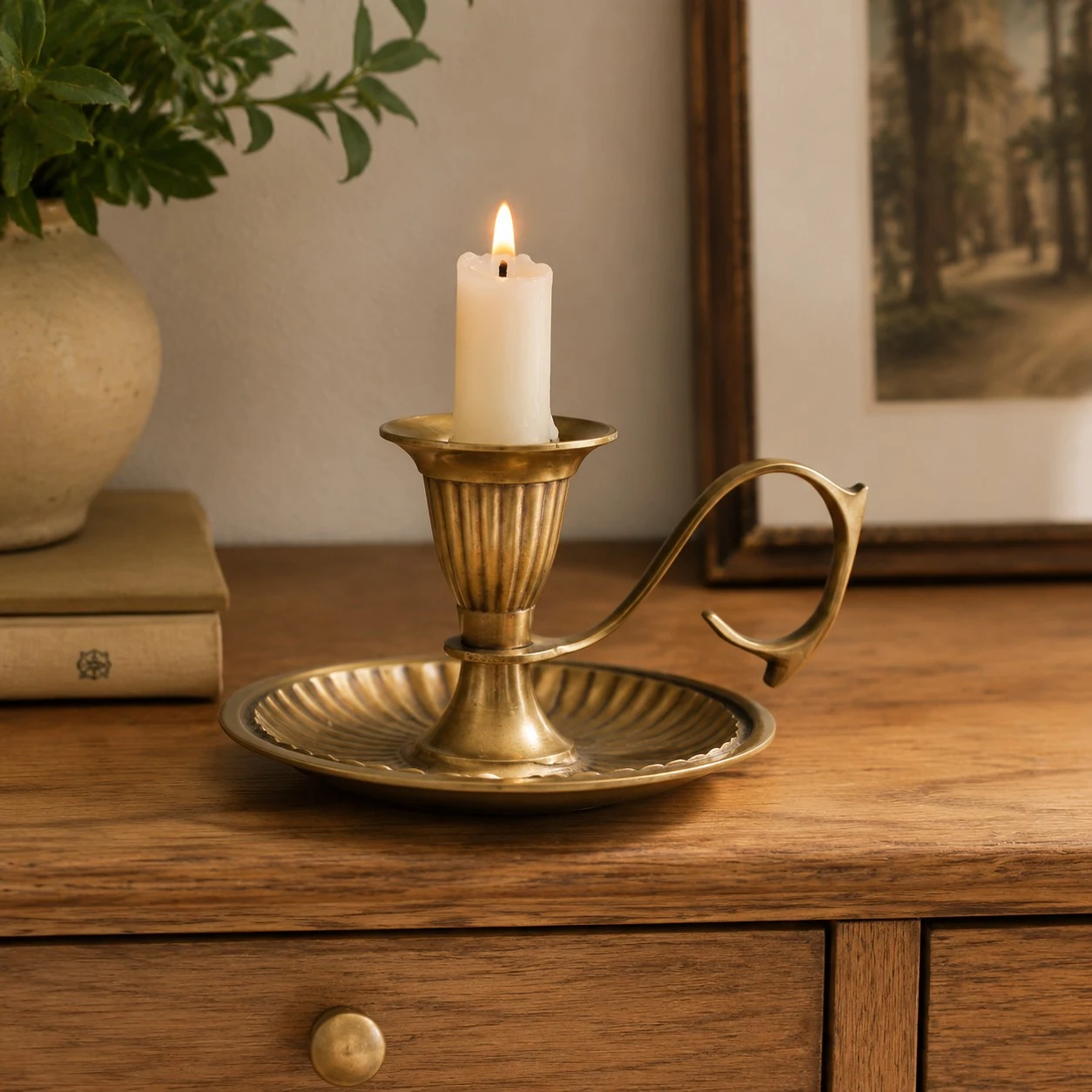 Aura brass candlestick with short candle on wooden cabinet