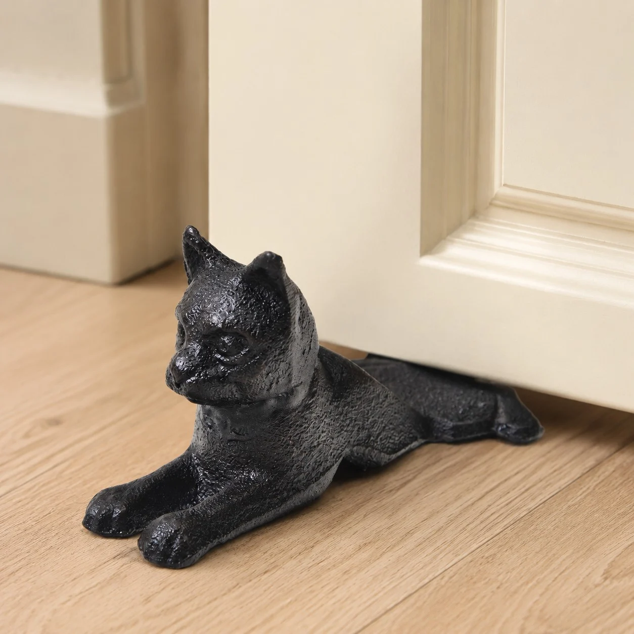 Guardian black cast iron cat door stopper beside an interior door