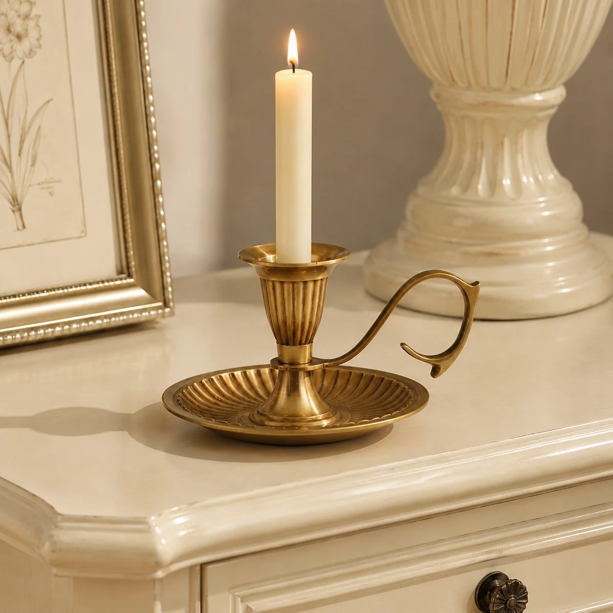 Aura brass candlestick with tall taper candle on cream console