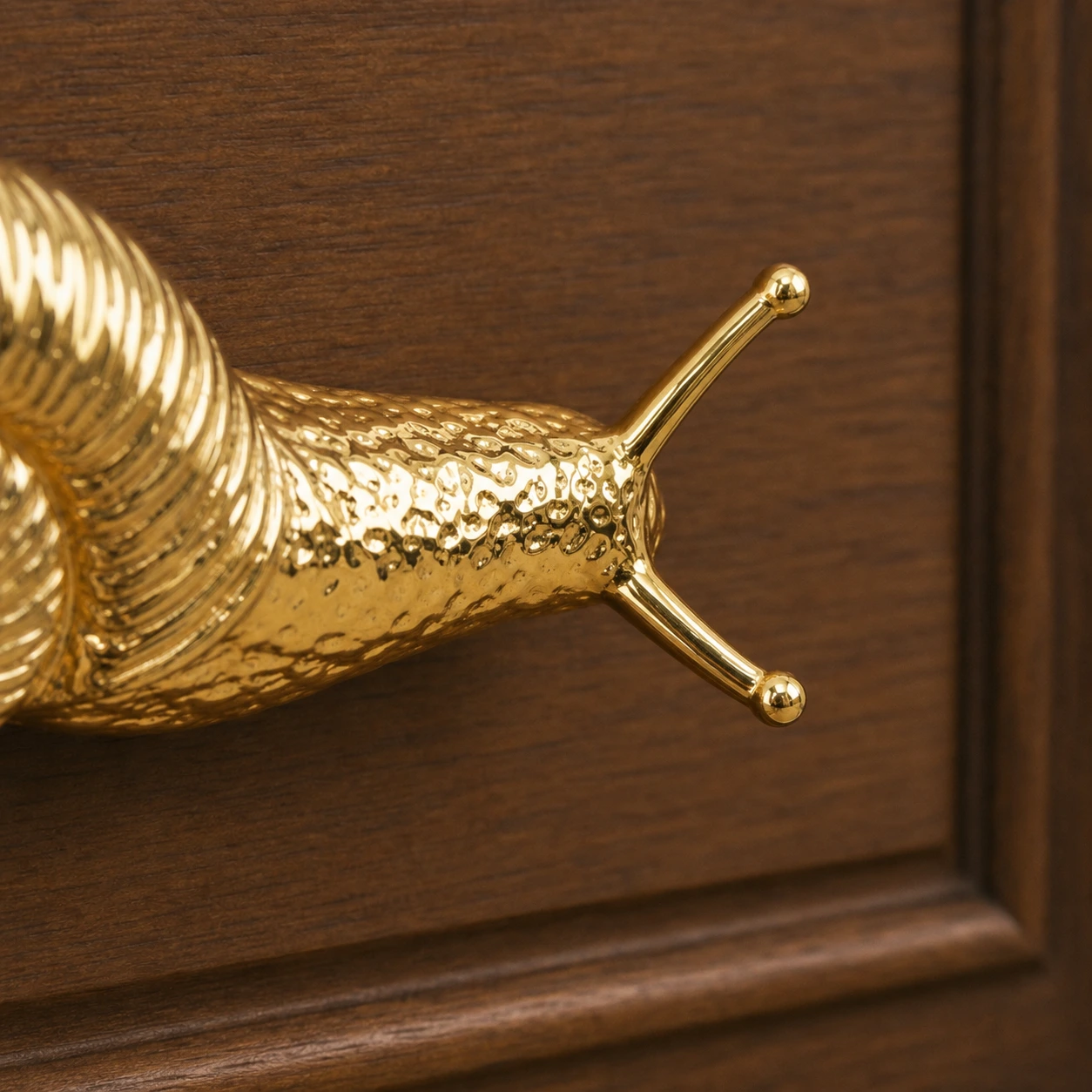 Close-up of the forked tail grip on the brass snail cabinet handle