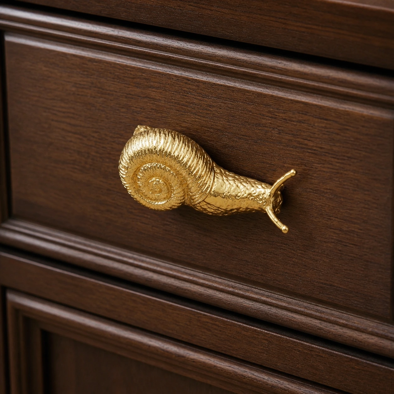 Mounted usage detail of the brass snail cabinet handle on a cabinet panel