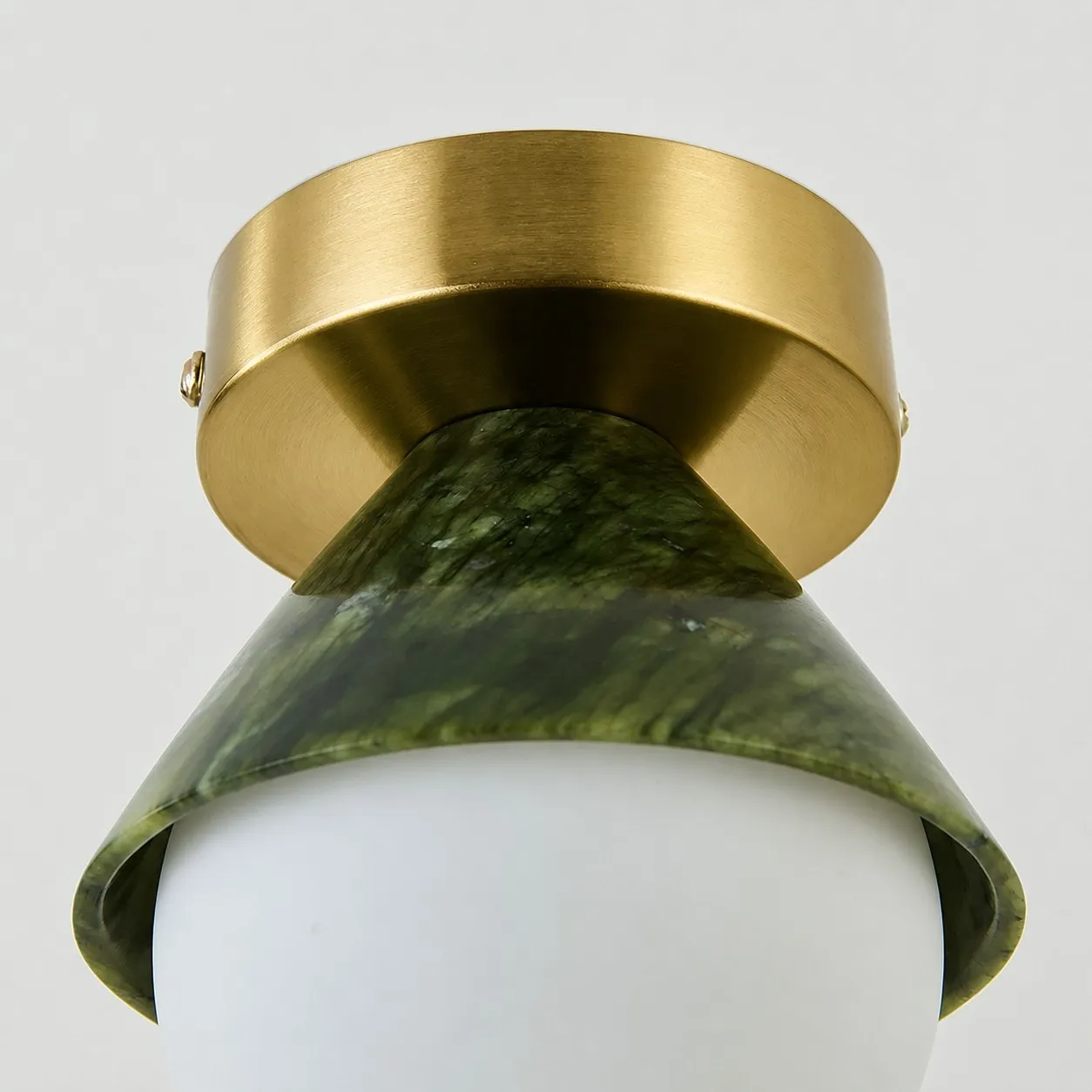 Close-up of brushed metal ceiling canopy and curved green shade