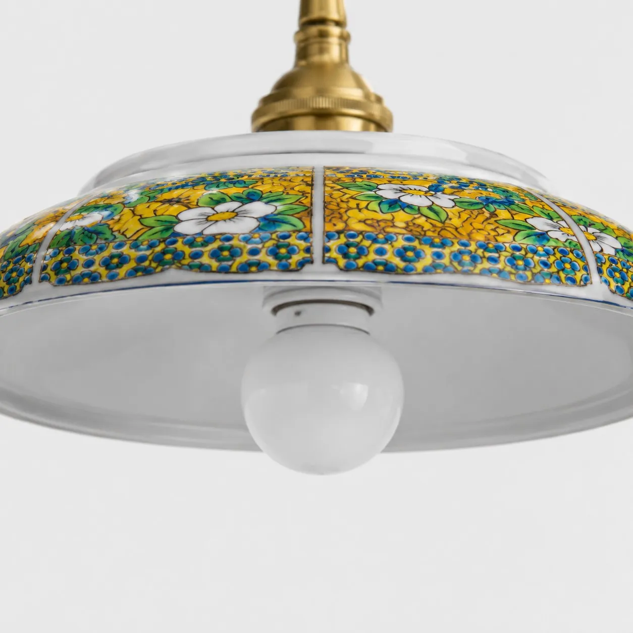 Close detail of yellow floral ceramic shade pattern and visible bulb opening