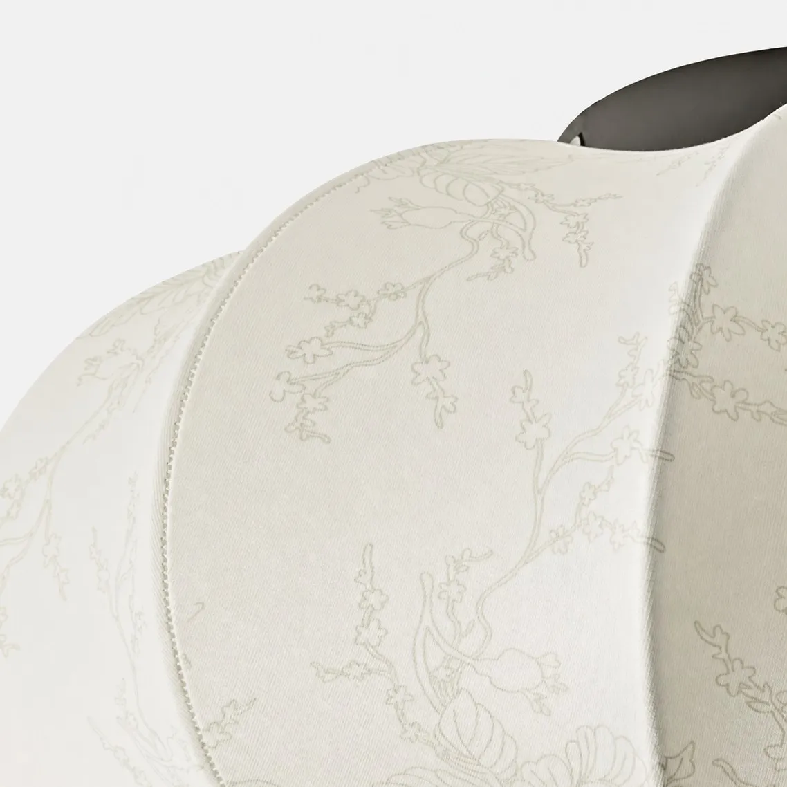 Close-up of cream floral fabric shade, pleated seams, and black top accent.