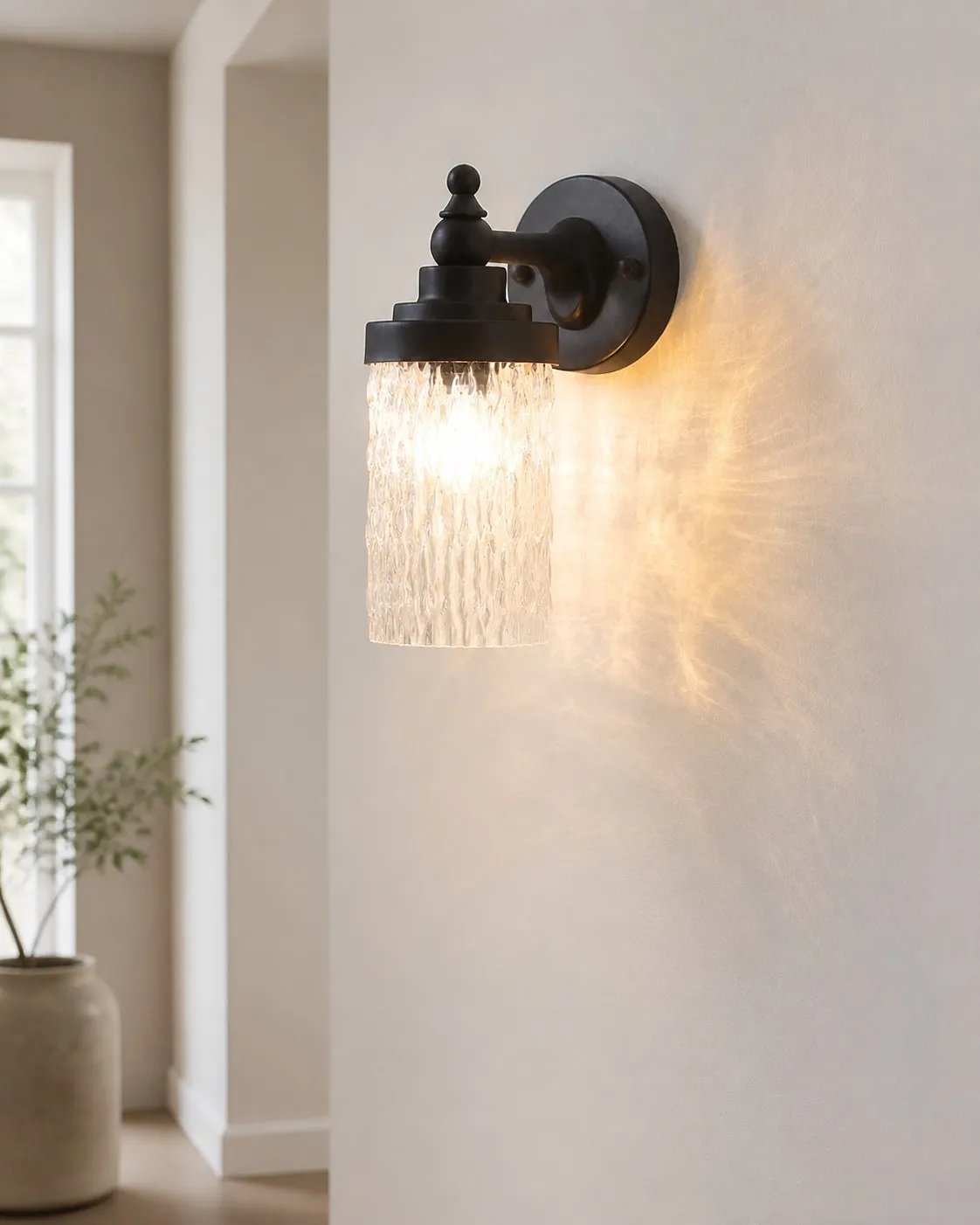 Averra matte black wall sconce casting warm light near an entryway