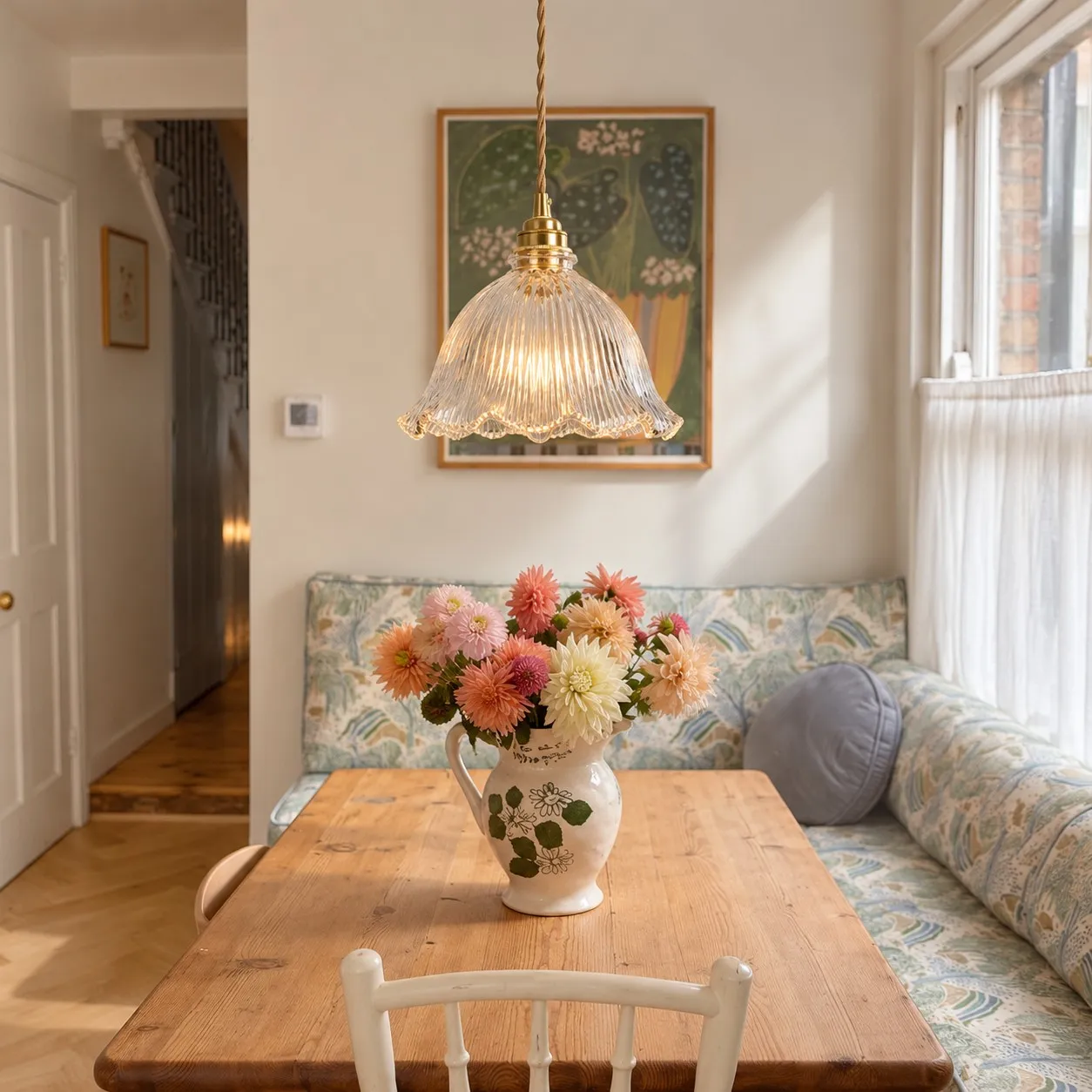 Blossix transparent glass pendant above a banquette